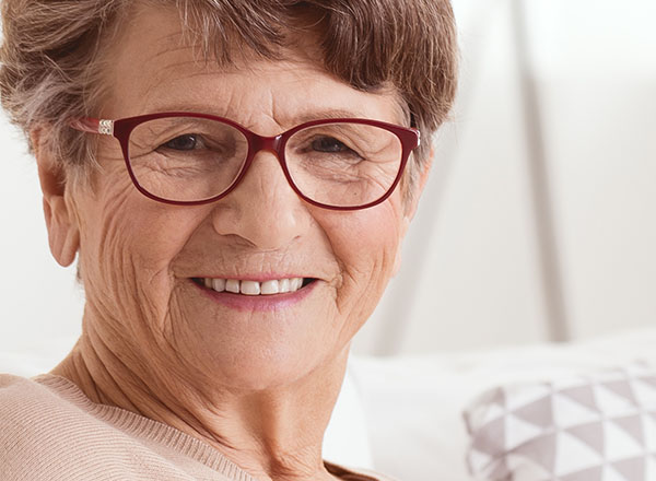 Happy senior lady sitting on the couch in retirement home