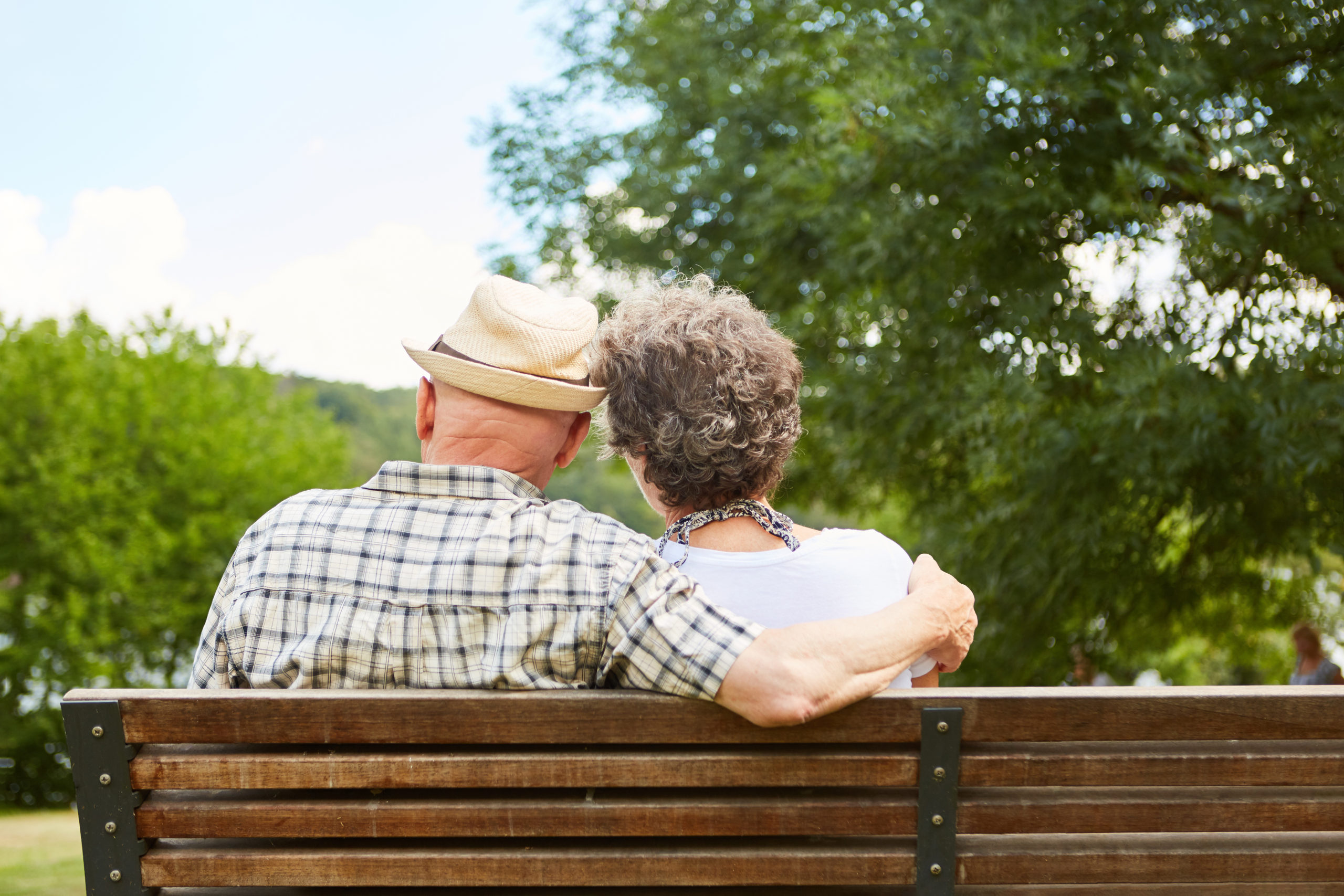 Senior couple sitting side by side on a park bench as a sign of harmony and love